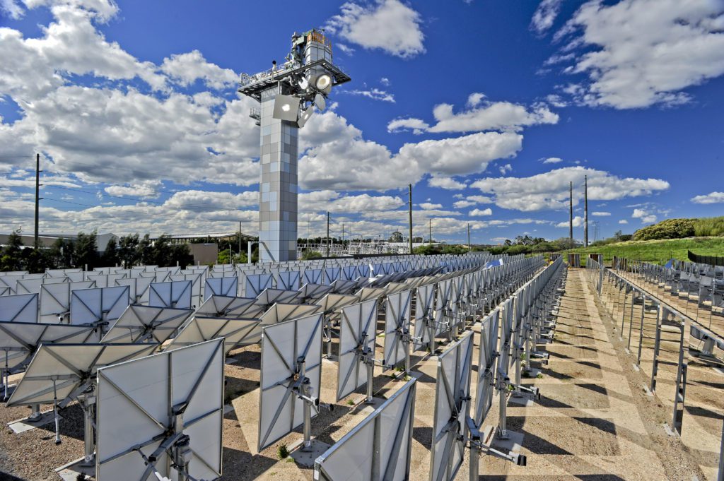 Solar field with tower on a sunny day with some clouds and power lines